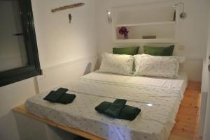 a bed with two green pillows on top of it at Charming Cottage on the sea turtle beach in Apolakkiá