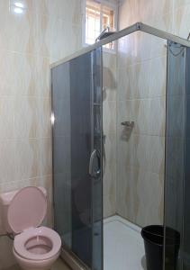 a bathroom with a toilet and a glass shower at GRACEPOINT APARTMENT in Rubuchi