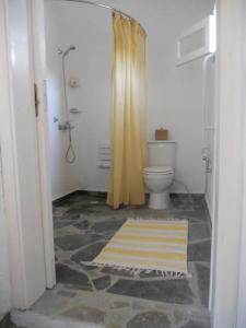 a bathroom with a toilet and a yellow shower curtain at Charming Cottage on the sea turtle beach in Apolakkiá