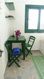 a green table and a chair in a room at Charming Cottage on the sea turtle beach in Apolakkiá