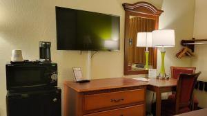 a hotel room with a desk and a television on the wall at Super 8 by Wyndham Canton/Livonia Area in Canton