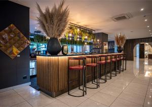 um bar com uma fila de bancos num restaurante em The Catalyst Apartment Hotel by NEWMARK em Joanesburgo