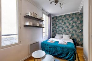 um pequeno quarto com uma cama com um cobertor azul em 316 Suite BIOT 6 - Superb apartment in Paris em Paris