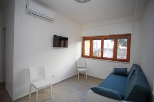 sala de estar con sofá azul y ventana en Agio Apartments Diamante - Bilocale, en Diamante