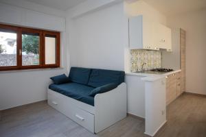Habitación con sofá azul en la cocina en Agio Apartments Diamante - Bilocale, en Diamante