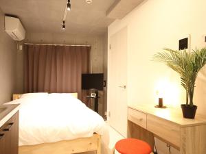 东京Tokyo Time Traveler 駅徒歩5分 暮らすように泊まれるホテル的一间卧室配有一张床和一张带盆栽的桌子