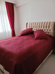 ein Bett mit roter Bettwäsche und Kissen in einem Schlafzimmer in der Unterkunft Vacation Apartment Апартаменты в Алании in Mahmutlar
