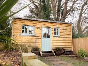 a tiny house with a blue door in a yard at Shepherd's Hut at The Granary in Steyning