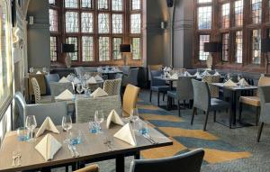 een restaurant met tafels, stoelen en ramen bij Abbey House Hotel in Barrow in Furness