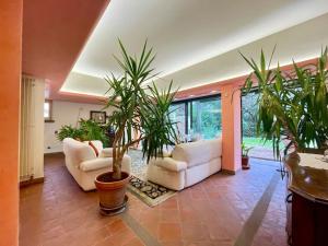 uma sala de estar com dois sofás brancos e vasos de plantas em Incantevole Villa con Giardino em Florença