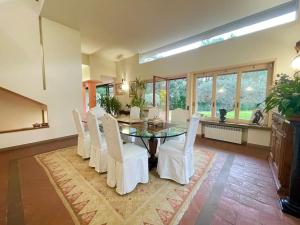 uma sala de jantar com uma mesa de vidro e cadeiras brancas em Incantevole Villa con Giardino em Florença
