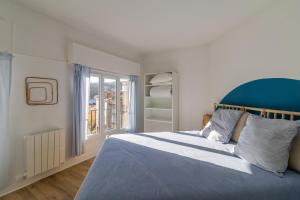 1 dormitorio con 1 cama con cabecero azul y ventana en L' Oriol à Chatel-Guyon, en Châtel-Guyon