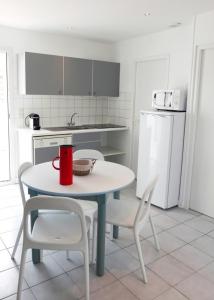 a kitchen with a table and chairs with a red mug on it at Le Petit Bois in Sainte-Marie-de-Ré