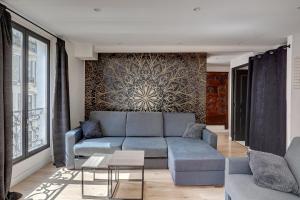 a living room with a blue couch and a wall at 303 Suite Simha - Superbe Appartement à Paris in Paris