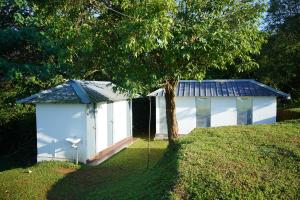 a white shed with a blue roof next to a tree at Campper Eagle View Point Vagamon in Idukki