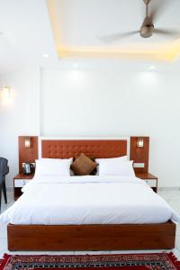 1 dormitorio con 1 cama grande con sábanas blancas en PADMA VILLAGE, en Thodupuzha