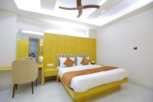 a bedroom with a bed and a desk and a chair at Hotel The Glitz in New Delhi