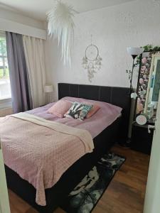 a bedroom with a bed with a pink comforter at Kaunis kaksio lähellä rautatieasemaa in Hämeenlinna