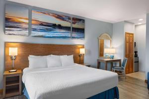 a hotel room with a bed and a desk with a table sidx sidx at Days Inn by Wyndham Kill Devil Hills Oceanfront - Wilbur in Kill Devil Hills