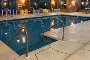 a swimming pool with blue and yellow chairs at Baymont by Wyndham La Crosse/Onalaska in Onalaska