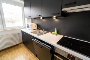 eine Küche mit einer Spüle und einer Mikrowelle in der Unterkunft ATRIUM - moderne, großzügige Wohnung EG MARIE in Ludwigshafen am Rhein
