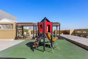a playground with a slide in a backyard at Al Khoory Hotel Apartments Al Barsha in Dubai