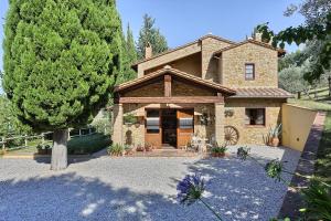 une grande maison en pierre avec un arbre en face de celle-ci dans l'établissement Villa Rivoltino di Sopra Volterra, à Montaperti