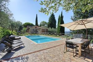- une piscine avec une table, des chaises et un parasol dans l'établissement Villa Rivoltino di Sopra Volterra, à Montaperti