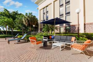 a patio with chairs and a couch and an umbrella at Hampton Inn Ft. Lauderdale-Cypress Creek in Fort Lauderdale