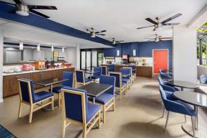 a restaurant with blue chairs and tables and a kitchen at Hampton Inn Ft. Lauderdale-Cypress Creek in Fort Lauderdale