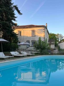 a house and a swimming pool in front of a house at Maison Favori in Le Beugnon