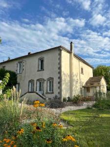 an old house with a garden in front of it at Maison Favori in Le Beugnon