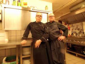 two men standing in a kitchen posing for a picture at Pension & Restaurant "Alte Schule" in Kluis