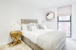 een witte slaapkamer met een groot bed en een spiegel bij Large 2 Bed Apartment London Catford Lewisham - Perfect for Long Stays in Londen