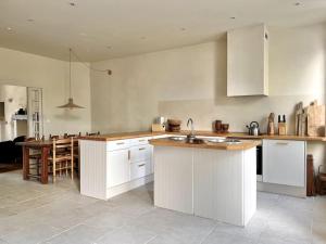a kitchen with white cabinets and a table in it at Maison Favori in Le Beugnon
