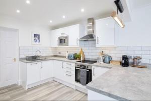 a white kitchen with white cabinets and appliances at The Dolman at Ferndown Forest Golf Course in Ferndown