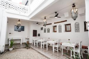uma sala de jantar com mesas brancas e cadeiras brancas em Zanzi House em Zanzibar