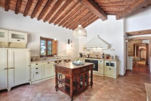 une cuisine avec des placards blancs et une table en bois dans l'établissement Villa Rivoltino di Sopra Volterra, à Montaperti
