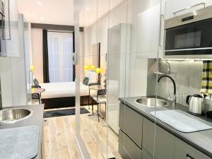 a white kitchen with two sinks and a bedroom at Charming Studette Paris La Défense in Puteaux