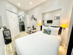 a bedroom with a large white bed and a kitchen at Charming Studette Paris La Défense in Puteaux