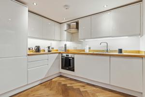 uma cozinha branca com pisos em madeira e armários brancos em Heavenly Stays - Victoria em Londres