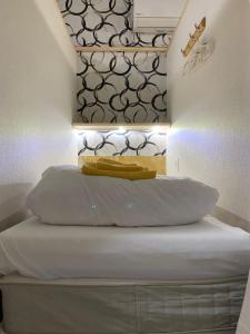 una camera da letto con un letto con lenzuola bianche e un muro di Shinjuku Sky hostel a Tokyo