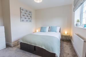 a bedroom with a bed with blue pillows and a window at Pine Trees - 4 bed home in The Witterings in Chichester