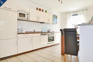 a kitchen with white cabinets and a black chair at Haus Triade Ferienwohnung Triade 2 in Zinnowitz