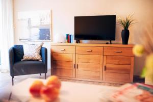 a living room with a television on a wooden dresser at Haus Jelena Appartement 1 in Borkum
