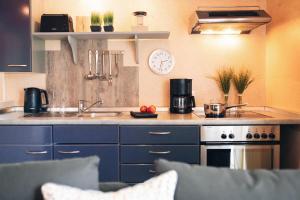 eine Küche mit blauen Schränken, einer Spüle und einer Uhr in der Unterkunft Haus Jelena Appartement 5 in Borkum