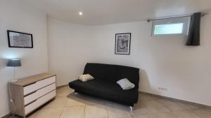 een zwarte bank in een woonkamer met een raam bij studio Les merles à Saint-Égrève in Saint-Égrève