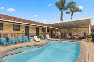 uma piscina com cadeiras azuis e um pátio em Comfort Inn Glenelg em Adelaide