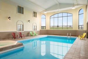 a large swimming pool with blue water in a building at Days Inn by Wyndham Swift Current in Swift Current