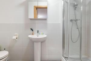 biała łazienka z umywalką i prysznicem w obiekcie Tranquil Urban Haven w Londynie